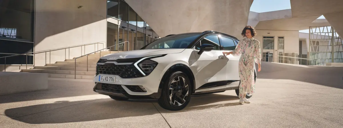 Kia Frau mit Kia Fahrzeug vor Freitreppe