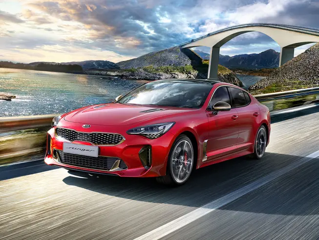 Kia Stinger Frontansicht in rot auf Strasse neben Fluss und Br&uuml;cke