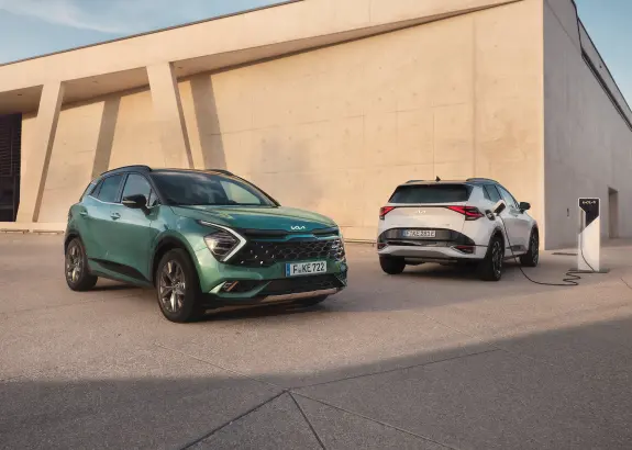 Kia Niro EV und Kia Sportage Plug-in Hybrid mit Lades&auml;ule vor Fitnessstudio