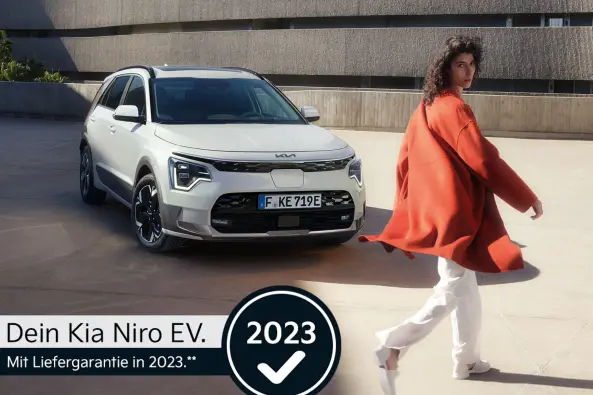kia Niro EV. mit Frau in organenem Mantel und dunklen Haaren und Logo 